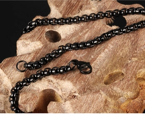 Macro view of black plated stainless steel box chain with secure lobster clasp on wood