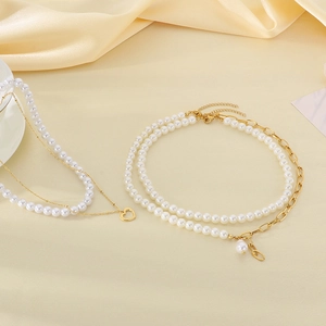 Baroque pearl layered necklace set with gold chain and heart pendant on silk background