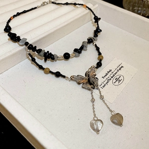 Detail of double-layer necklace with black beads, butterfly pendant and crystal hearts