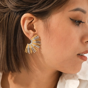 Close-up of a two-tone fan-shaped stainless steel earring worn on a female model's ear
