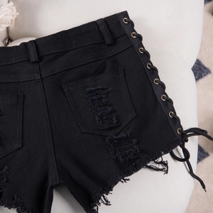 Dettaglio degli shorts in denim nero con lacci laterali e accenti di occhielli in metallo