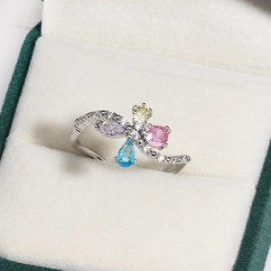 Detail of wavy silver ring featuring colorful butterfly zircon gems in a jewelry box