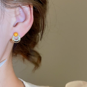 Close-up of geometric opal stud earrings with gold twisted rope and pavé crystals