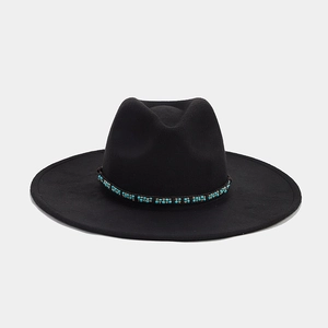 Detail of wide brim fedora hat featuring green and gold beaded ethnic style band decoration