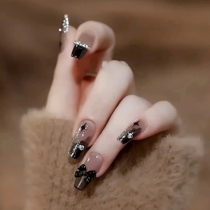 Detail view of black gradient long coffin nails with bow, rhinestones and glitter accents