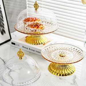 Close-up of glass cake stand with golden base and transparent dome lid for desserts