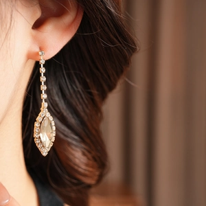 Detail of long gold diamond earrings with crystal tassels on a model's ear