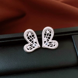 Détail macro de boucles d'oreilles cœur asymétriques plaquées or 18K avec zircons brillants