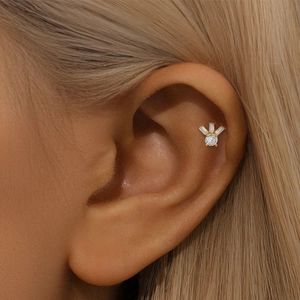 Detail of a gold plated stud earring with heart fan-shaped cubic zirconia on the ear