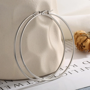Detailed view of large polished silver hoop earrings resting against ceramic decor