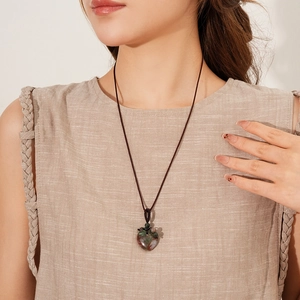 Detailed close-up of heart-shaped agate stone pendant on a brown woven rope necklace