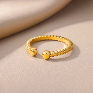 Detail of twisted rope ring in 18k gold plated stainless steel on luxury silk fabric