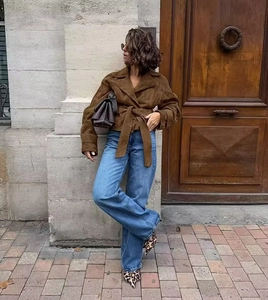 Detail of brown suede jacket styled with blue jeans and leopard print heels