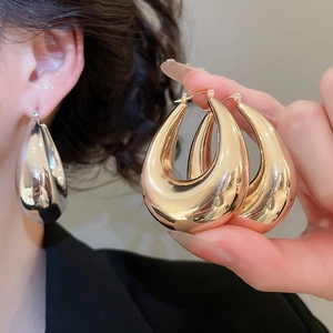Detailed close-up of chunky gold and silver U-shaped hoop earrings with mirror finish