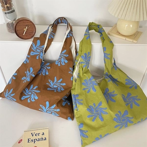 Detail view of two large floral canvas tote bags in brown and green with wide shoulder straps