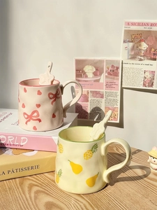 Detail of pink bow and fruit pattern ceramic mugs with star-shaped spoons on set