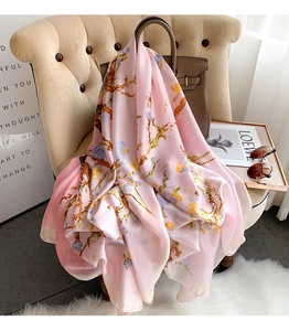 Detail of pink silk scarf with floral almond blossom print draped on a chair