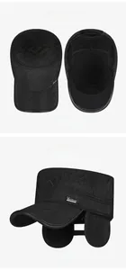 Detail view of quilted thermal winter hat with ear flaps and metal letter logo badge