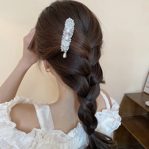 Detail of elegant pearl flower hair clip on braided hair with shell texture accents