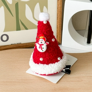 Detail of red plush Christmas hat hair clip with snowman pendant on wooden surface