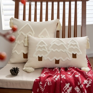 Weihnachtskissenbezüge mit getufteten Bäumen und Quasten auf einem Holzstuhl mit Decke