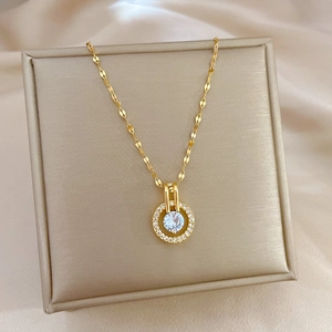 Collana in titanio dorato con ciondolo in zircone in una scatola per gioielli beige