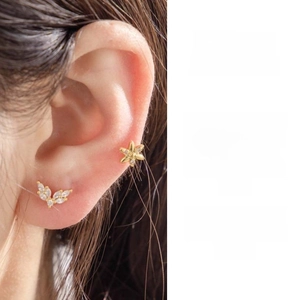 Detail of gold flower and winged leaf earrings showing fit and design on ear