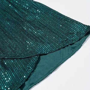 Close-up of deep green sequins on a slim V-neck dress showing texture and shine