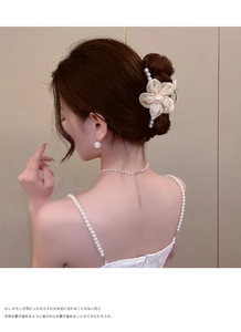 Detail of elegant beige floral hair claw clip with pearls and tassels on a model hair