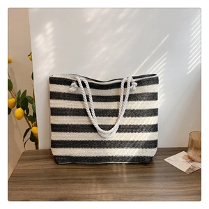 Detail of black and white striped straw tote bag with rope handle and summer texture