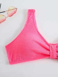 Detail view of neon pink seersucker bikini top with textured fabric and stylish sunglasses