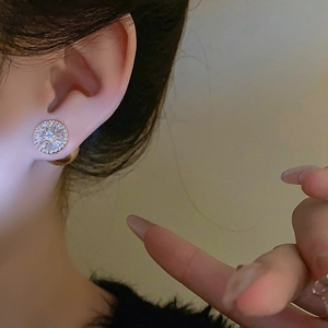 Gros plan de boucles d'oreilles dorées avec perles et zircons portées par un mannequin