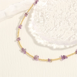 Detail of irregular purple amethyst gravel and gold beads on a handmade necklace
