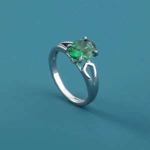 Macro shot of a silver ring with a large oval green gemstone and zircon settings