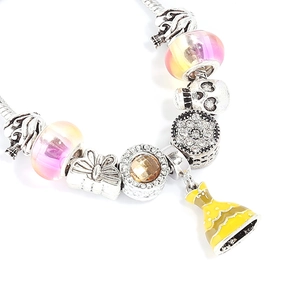 Macro shot of silver charm bracelet featuring pink and yellow glass beads and dress pendant