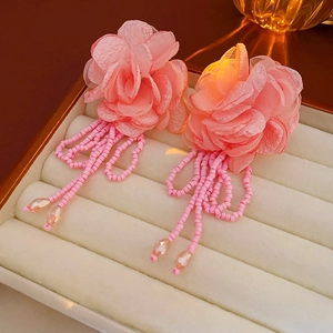 Macro detail of pink fabric flower petals and long beaded tassels with teardrop crystal