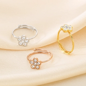 Elegant flower-shaped crystal rings in silver, gold, and rose gold on silk fabric