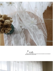 Détail de la broderie florale de marguerites sur rideaux en dentelle semi-transparents