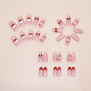 Close-up of pink glitter press-on nails with cherry, bow, and Christmas hat designs