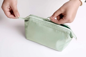 Detail showing the smooth zipper closure on a pale green waterproof makeup storage bag