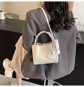 Close-up of off-white lychee grain tote bag with plaid silk scarf and leather tag