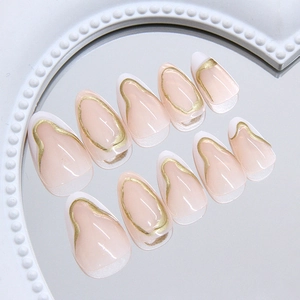Faux ongles amande rose nude avec pointes blanches et lignes ondulées dorées