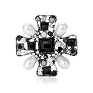 Vintage Baroque cross brooch with black gemstones and pearls on white background