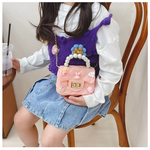 Pink quilted girls' crossbody bag with pearl handle and cute cartoon charms shown on model