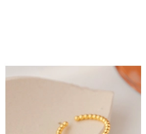 Détail des créoles dorées en forme de C avec texture perlée de style bambou chic