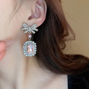 Détail de boucles d'oreilles en cristal rose avec nœud strass et finition argent