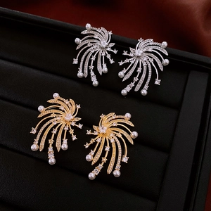 Detail of star-shaped zircon and pearl earrings in gold and silver finishes
