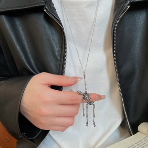 Detail of silver skull pendant necklace with tassel design on a leather jacket outfit