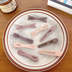Set of 9 matte milk coffee hair clips with X-shape and hollow oval designs in ceramic tray