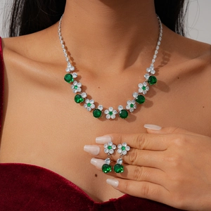 Close-up of green emerald flower necklace and earrings set on a model in red velvet dress